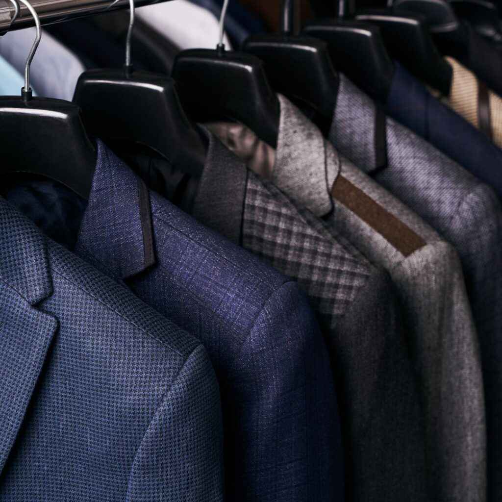 Flera kostymer i olika färger, material och design hänger i butik.