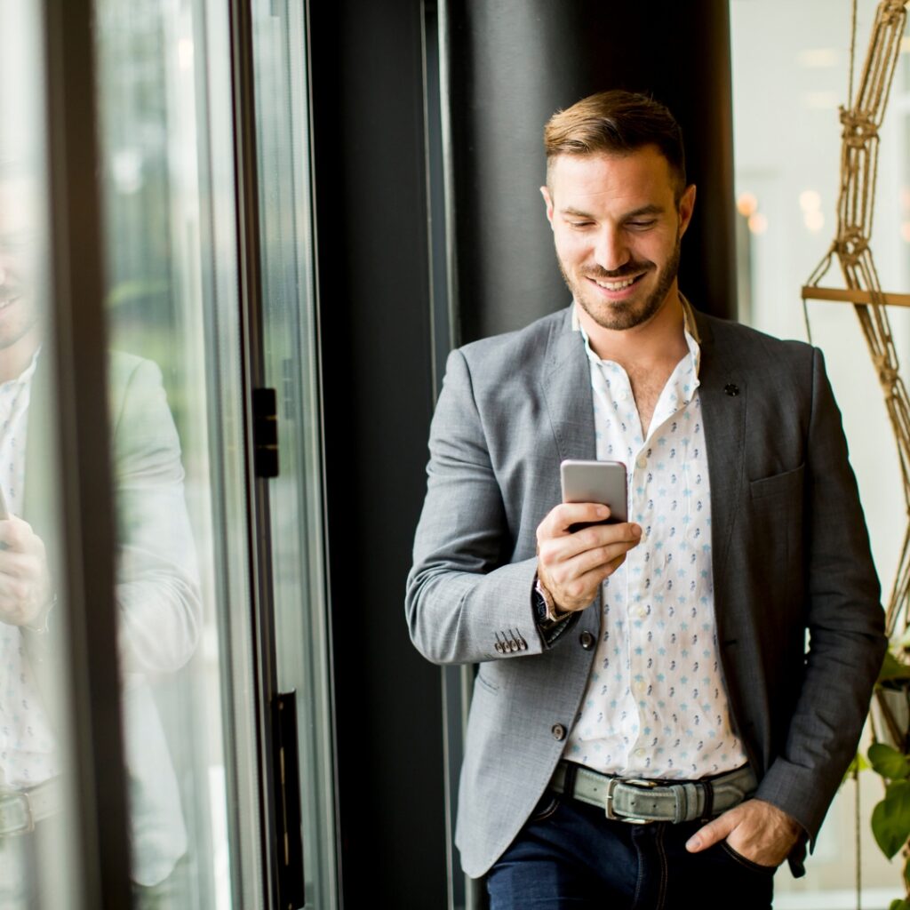 Man med smart casual klädkod skriver meddelande på mobilen